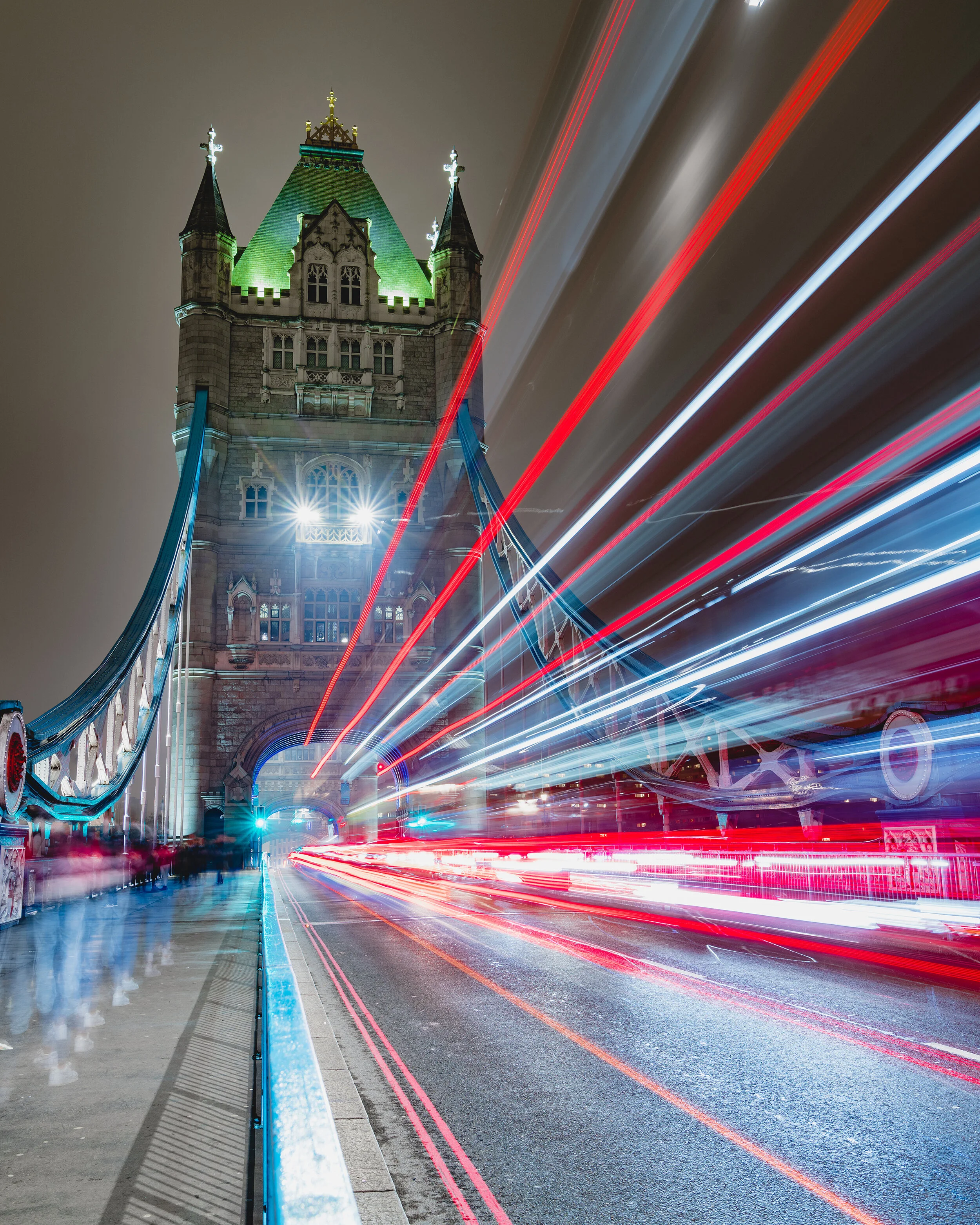 Light trails from city buses pass through Tower Bridge at night